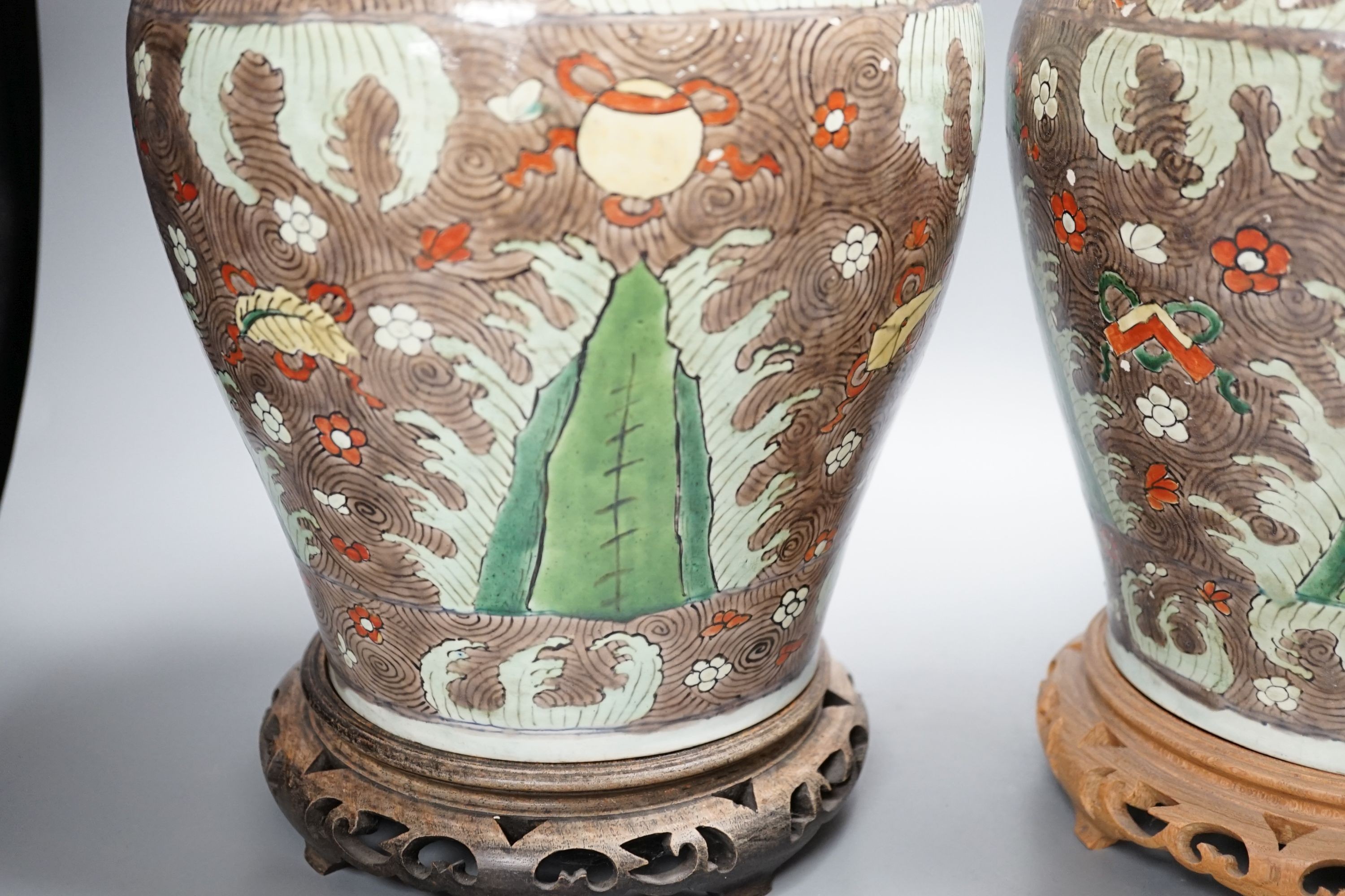 A pair of Chinese enamelled porcelain jars and covers, in Transitional style, 34cm high, wood stands